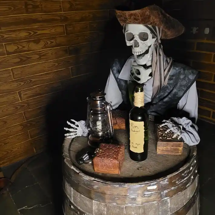 un eskeleto de un pirata con una botella de ron y un barril