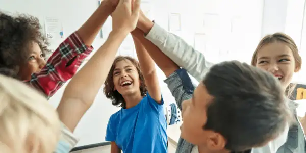 Adolescentes trabajando juntos para resolver un reto y chocando las manos en señal de celebración tras lograrlo en equipo.