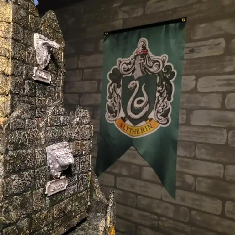 Escudo de casa de magia sobre pared de piedra en la sala La Maldición del Hechicero en El Poblado Medellín