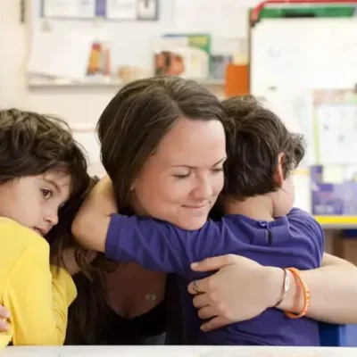 Mujer abrazando y protegiendo a dos niños, transmitiendo seguridad, cuidado y protección en un entorno familiar.